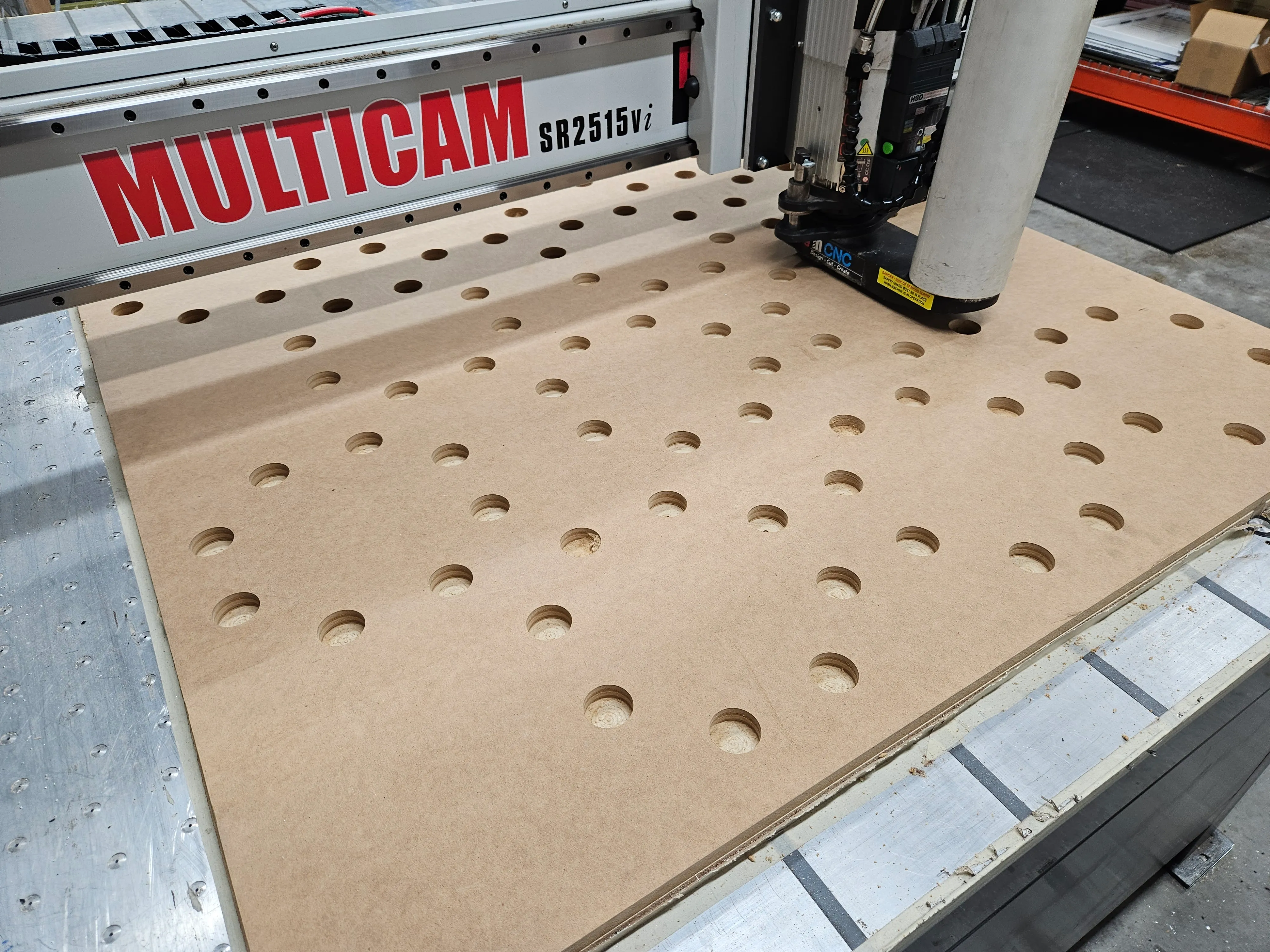 MDF template panel mid-cut on the Multicam SR2515vi, perimeter holes already drilled