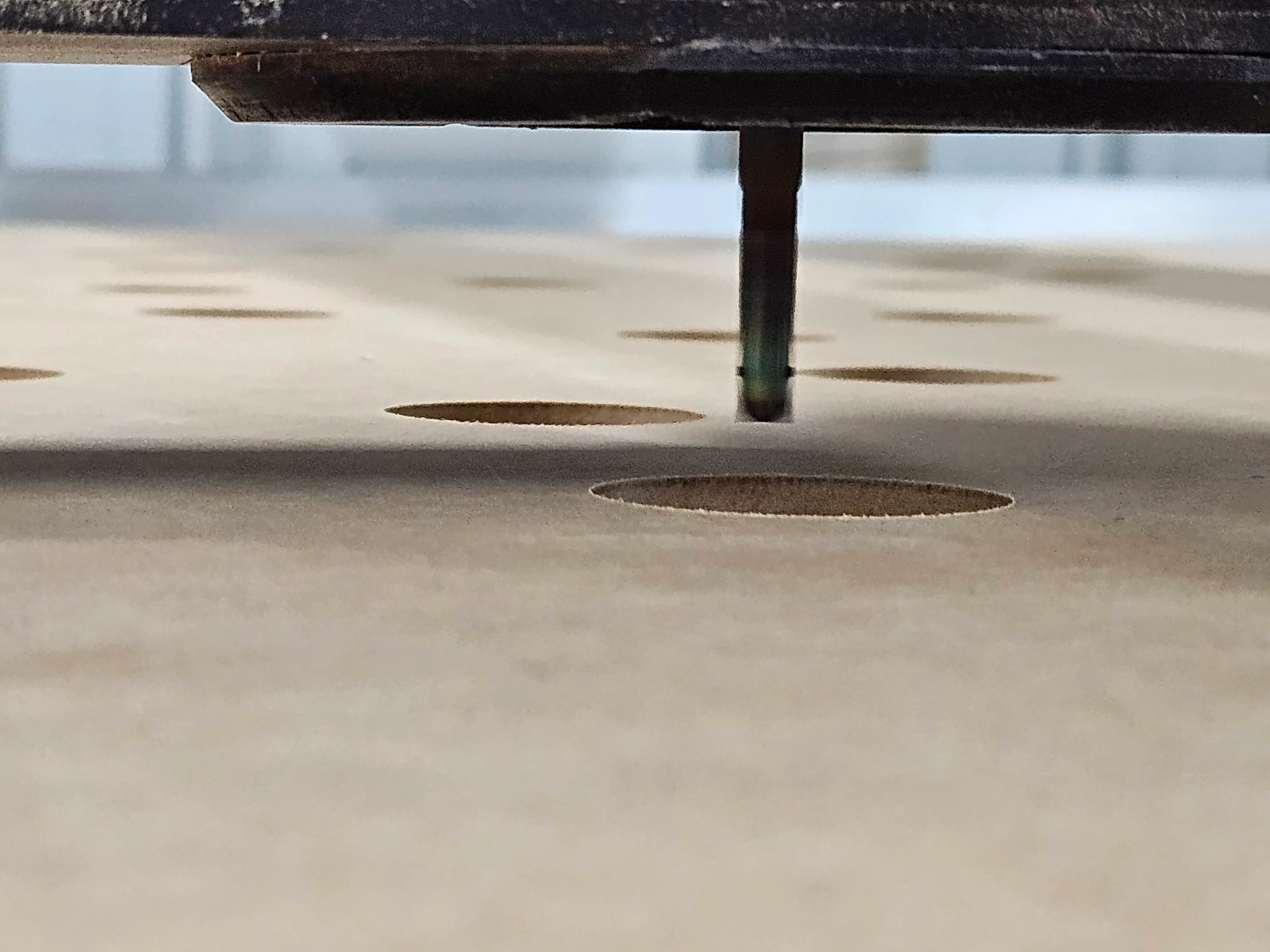 Macro close-up of the cutting bit drilling a bolt hole through the MDF